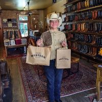 Young customer in western wear holding newly purchased bags at (Mid)Western Second Hand shop in Somerset, Perry County, Ohio.