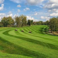 Three groundskeepers on mowers riding across greens at Whitetail Ridge Golf Course in Thornville, Perry County, Ohio