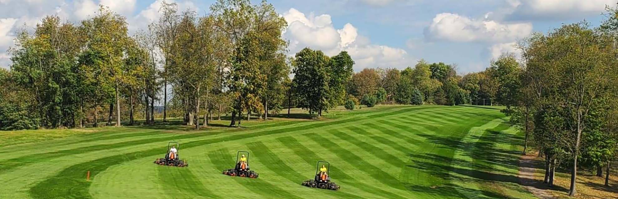 Three groundskeepers on mowers riding across greens at Whitetail Ridge Golf Course in Thornville, Perry County, Ohio