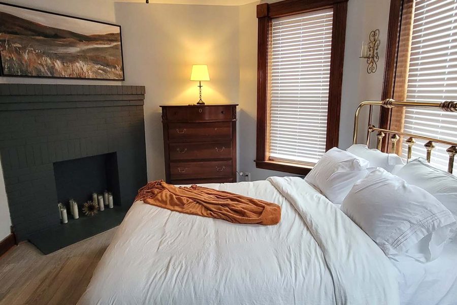 Antique brass bed in room with wooden dresser and decorative fireplace at the Uptown Belle lodging in New Lexington, Perry County, Ohio.