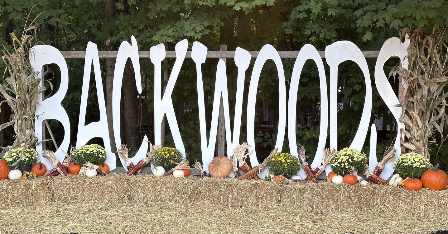 Sign reading "Backwoods" with a fall display in front.